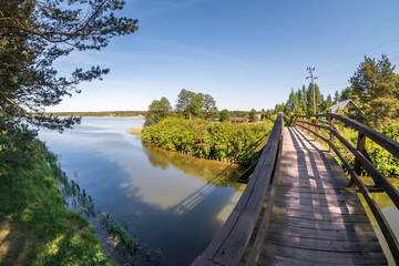 old wooden bridge across the river canal against the backdrop of the lake