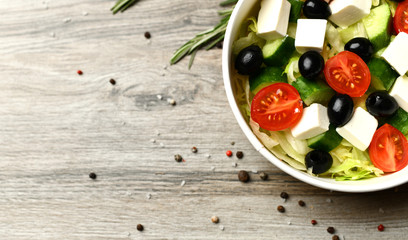 Vegetables greek salad on wooden background with space for text