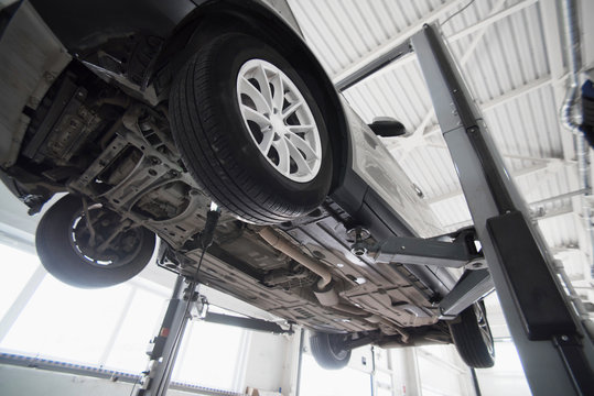 Car on a wheel alignment lift in auto service. Diagnosis of the chassis of the car raised at the elevator.