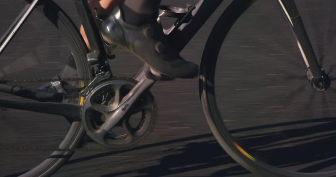 Slow motion close up of man cycling on road bike outside on desert road on sunny day 