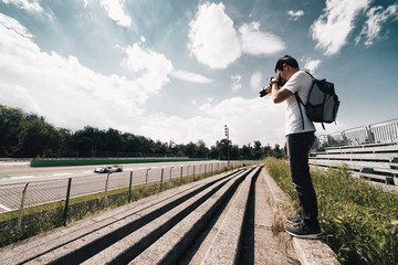 Amateur photographer taking photo to a sport car during racing cars - wide angle view