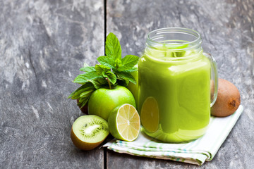 Obraz na płótnie Canvas Fresh smoothie with green fruits in a glass jar mug on wooden table