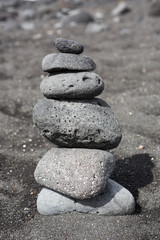 Fototapeta na wymiar Balanced stacked stones or pebbles on a black sand beach.