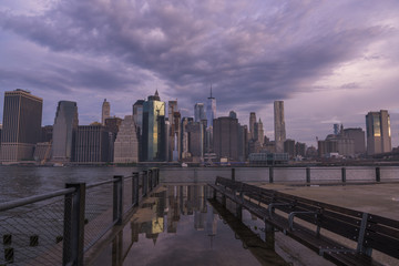 Obraz premium New York City skyline reflection in water puddle at Brooklyn Bridge Park on moody morning 
