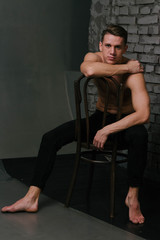 Fototapeta na wymiar Casually handsome. Studio shot of handsome young man sitting on the chair and looking at camera. bare chest