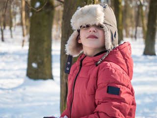 Cute little boy in red jacket at winter park background