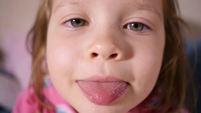 Little kid girl face portrait - grimace and show tongue closeup slow motion