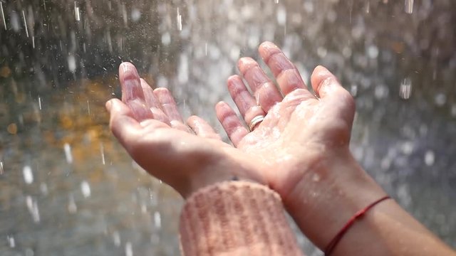 Human palms catching raindrops - abundance of water on the planet - long awaited rain