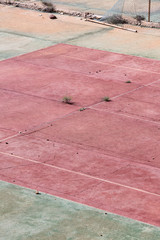 An empty and abandoned hardcourt tennis court.