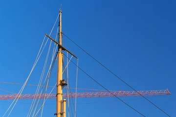 Ships mast with construction crane arm or jib in background.