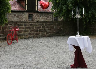 stylish table decoration with candlestick and red bicycle, in the background a red balloon flies away