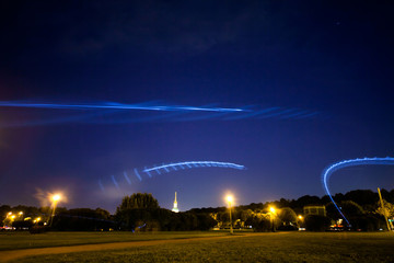 trajectory of the frozen light from the frisbee flying in the city park