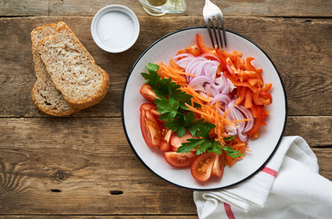 Vegetable salad with tomatoes, bell pepper, carrots, onion and parsley on a plate