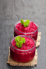 Beetroot  puree in glass jars on black stone background