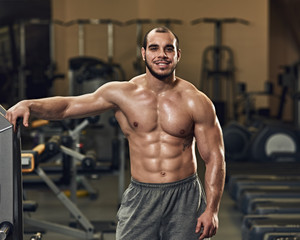 Fototapeta na wymiar Smiling happy young athlete posing in modern gym
