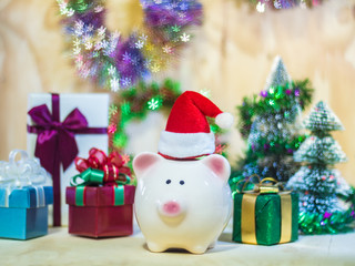 Piggy saving bank with Santa hat on wooden floor