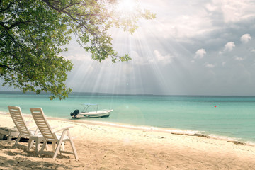 Loungers on a tropical beach, boat in the sea. A beautiful place for holidays
