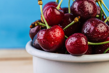 cherries in a white enamel mug on a wooden table, fresh cherry, seasonal berries, sweet cherry, ripe berries, berries in to the handle