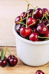 cherries in a white enamel mug on a wooden table, fresh cherry, seasonal berries, sweet cherry, ripe berries, berries in a mug