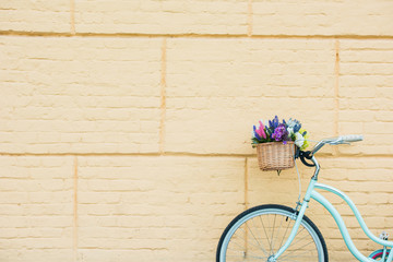 Fototapeta na wymiar white bicycle with beautiful flowers in basket near wall