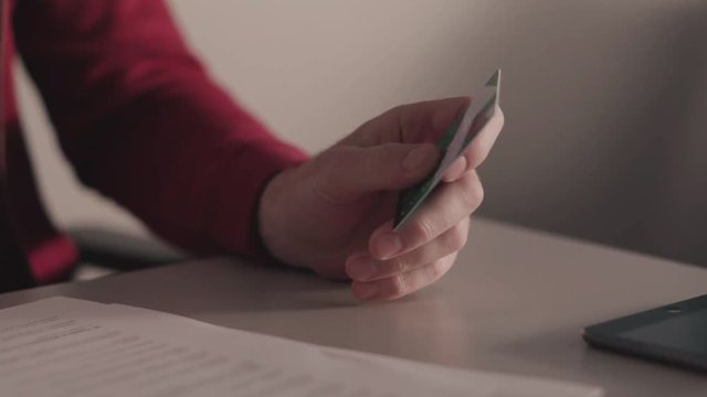 Online payments concept. Stock. Business man holds a credit card in his hand while using or typing identification numbers after buying goods from retailer stores via the internet