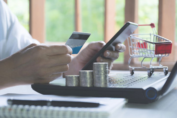 Hands holding blue credit card and using a laptop for online shopping concept.