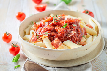 Tasty penne bolognese with bacon and herbs