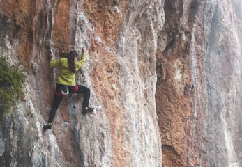 A woman climbs the rock.