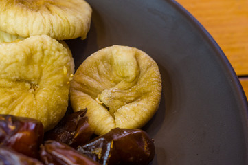 dried dates and figs in a ceramic plate on a wooden table