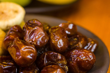 dried dates and figs in a ceramic plate on a wooden table