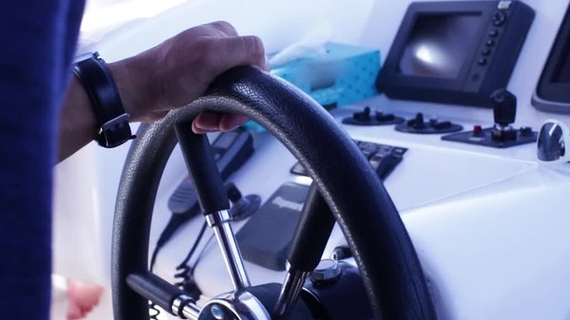 Captain behind the wheel of a luxury yacht. Stock. Closeup of the hands of men manoeuvre the yacht