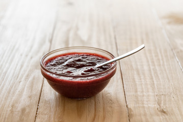 Homemade strawberry jam in a a glass bowl with fresh ripe strawberries on a wooden table