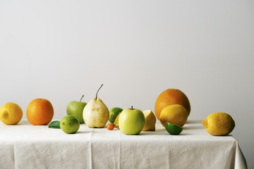 Citrus fruits, pear and apples on a table covered with linen tablecloth