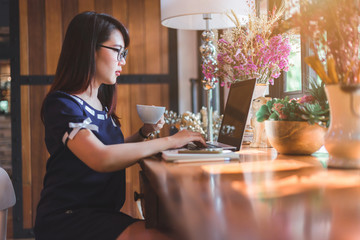 Asian business female working with laptop make a note in coffee shop like the background.