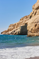 View of sandy beach, sealine, waves, cliff and blue sky in the summer sunny day
