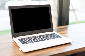 Mockup image of laptop with blank white screen on wooden table of In the coffee shop.