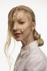 Portrait of a beautiful smiling blonde teenage girl. Conceptual makeup decorated with white pearls...