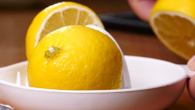 Slow motion close up of lemons on juice maker juicer squeezer. Healthy drinks concept.