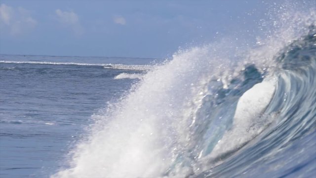 SLOW MOTION, CLOSE UP, DOF: Empty barrel wave rolling past the camera in sunny Pacific. Awesome shot of beautiful tube wave sparkling in the sunlight. Splashing ocean wave approaching the shoreline.
