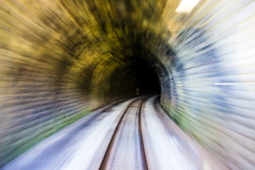 Abstract blurred background, conveying fast train speed along old tunnel railway from light to darkness. Concept speedy blurred motion backdrop