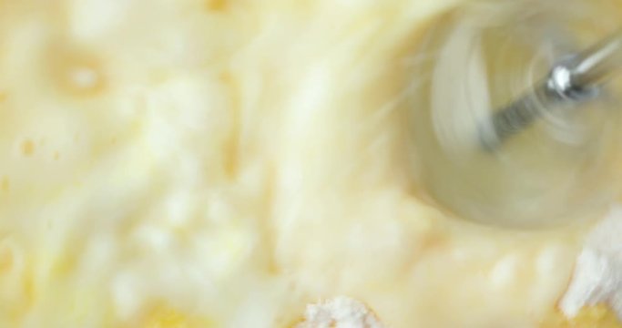 Close video of fresh milk and homemade banana cream pudding mix being rapidly mixed with beaters.