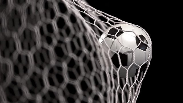 Beautiful soccer ball flies into net on a black background. The movement at the beginning is accelerated then slowly