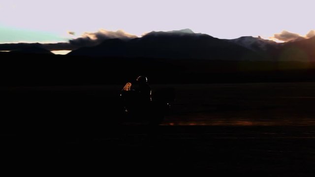 Silhouette of man crossing the desert in a motorcycle at sunset during a adventure travel