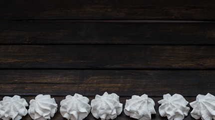 Sweet white meringue on a wooden background, free space for text. Top view.