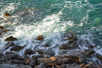 Huge stones in the sea and waves. Sea foam On a sunny day. View from above. Montenegro. The Budva Riviera