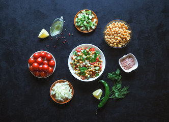 Summer vegetarian diet. Salad with chickpeas and vegetables on a black table.