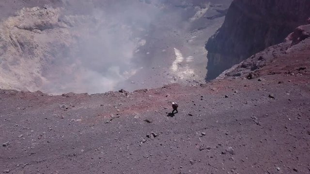 Mountaineer walking on the edge of a smoked volcano, Chile. Aerial view, 4k