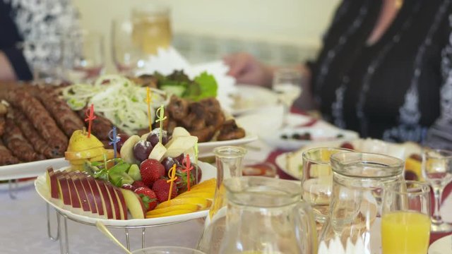 Dinner table served with lula kebabs and fresh vegetables. People enjoy Armenian style kebab at restaurant.