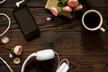 Smartphone, headphones, coffee cup on a wooden table. Top view flat lay background. Copy space.
