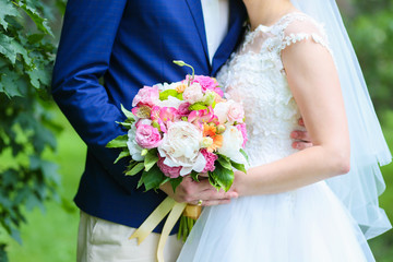 Obraz na płótnie Canvas the bride and groom hold in their hands a beautiful summer wedding bouquet of peonies